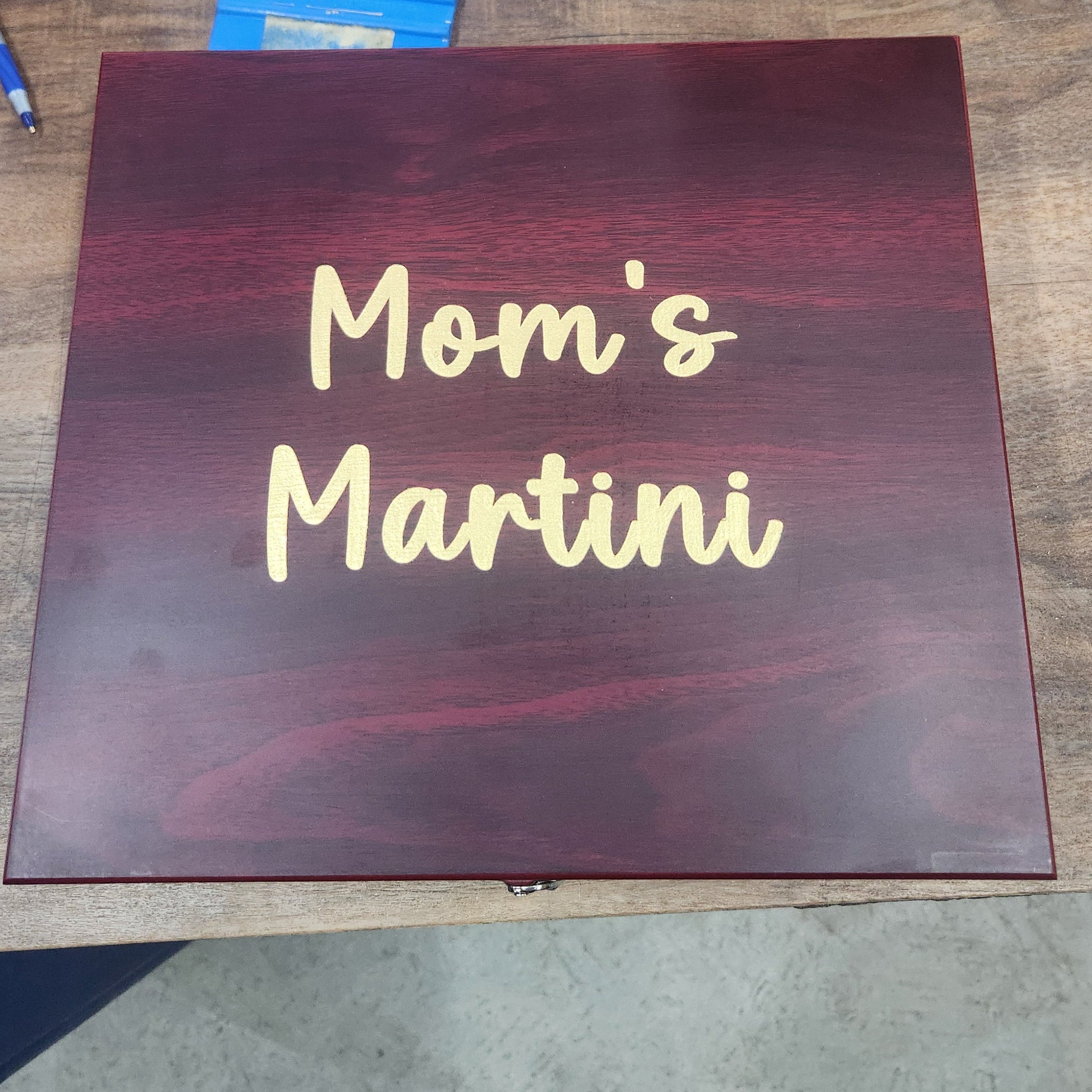 Custom engraved wooden gift box with 'Mom's Martini' in gold lettering on a wood table